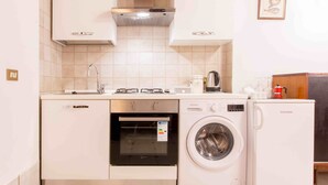 Une cuisine compacte équipée d’un lave-vaisselle, d’un four et d’un lave-linge.