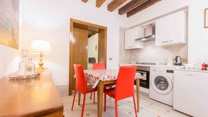 Une cuisine compacte comprenant une table à manger, des chaises, un lave-linge et une machine à café.