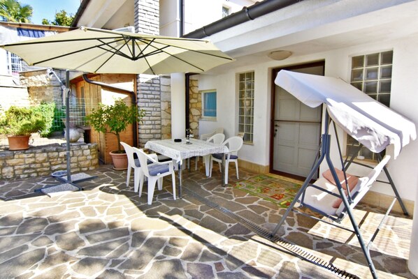 A patio area with stone flooring, a table with chairs, and a swing chair.
