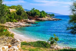 A coastal landscape with clear blue waters, rocky terrain, and greenery. - Nautilus-Bay Suites - Apt. 420 Three-room suite for 2-6 persons (Zavala)