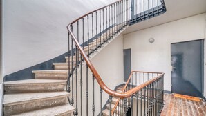 A staircase with a wooden handrail and metal balusters, leading to a landing with a door. - La Suite - Studio Apartment, Sleeps 2 (Bordeaux)
