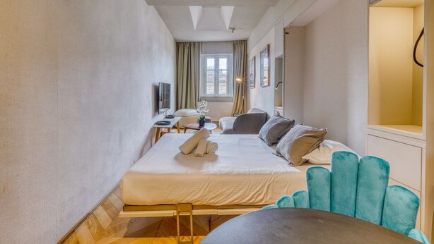 A hotel room with a bed, a desk, a chair, a TV, and a window. - La Suite - Studio Apartment, Sleeps 2 (Bordeaux)