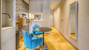 A modern kitchen with white cabinets, a blue chair, and a round table. - La Suite - Studio Apartment, Sleeps 2 (Bordeaux)