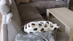 Ein Wohnzimmer mit grauem Sofa, einem Couchtisch und einem Gemälde eines Leuchtturms an der Wand.