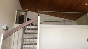 Eine Holztreppe mit Metallgeländer, die zu einer Zwischenebene im zweiten Obergeschoss führt.