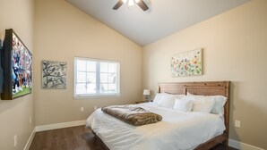 A bedroom with a wooden bed, a ceiling fan, and artwork on the walls. - Brand New Modern Guest House in the perfect Location. Safe, and comfortable. (Kalispell)