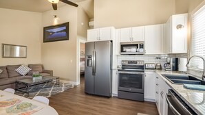 A modern kitchen with stainless steel appliances, white cabinetry, and a dining area with a wooden table and chairs.
