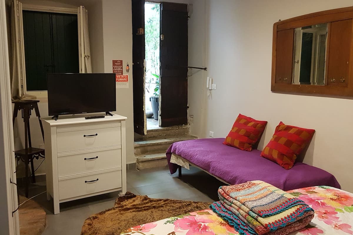 Une chambre à coucher avec un lit, une commode, un téléviseur et une fenêtre.
