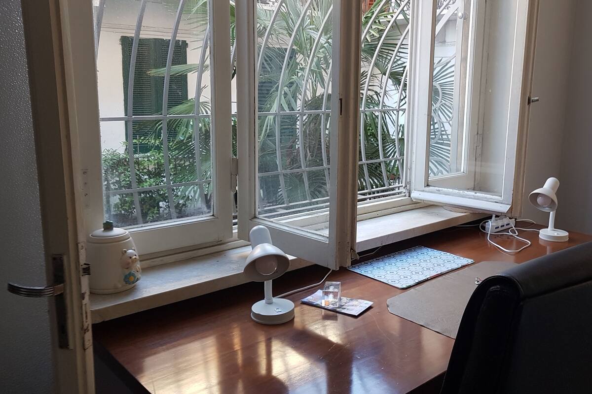 Une pièce comprenant un bureau en bois, deux lampes de bureau blanches, une petite table avec un clavier et une chaise.