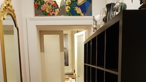 A hallway with a tiled floor, a white door, a black shelving unit, and a painting above the door. - La casa di Daniele (Brescia)