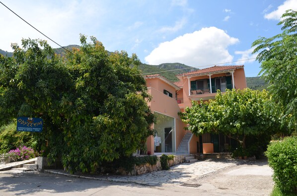Stunning two-story building with a balcony, glass door entrance, and lush green surroundings.