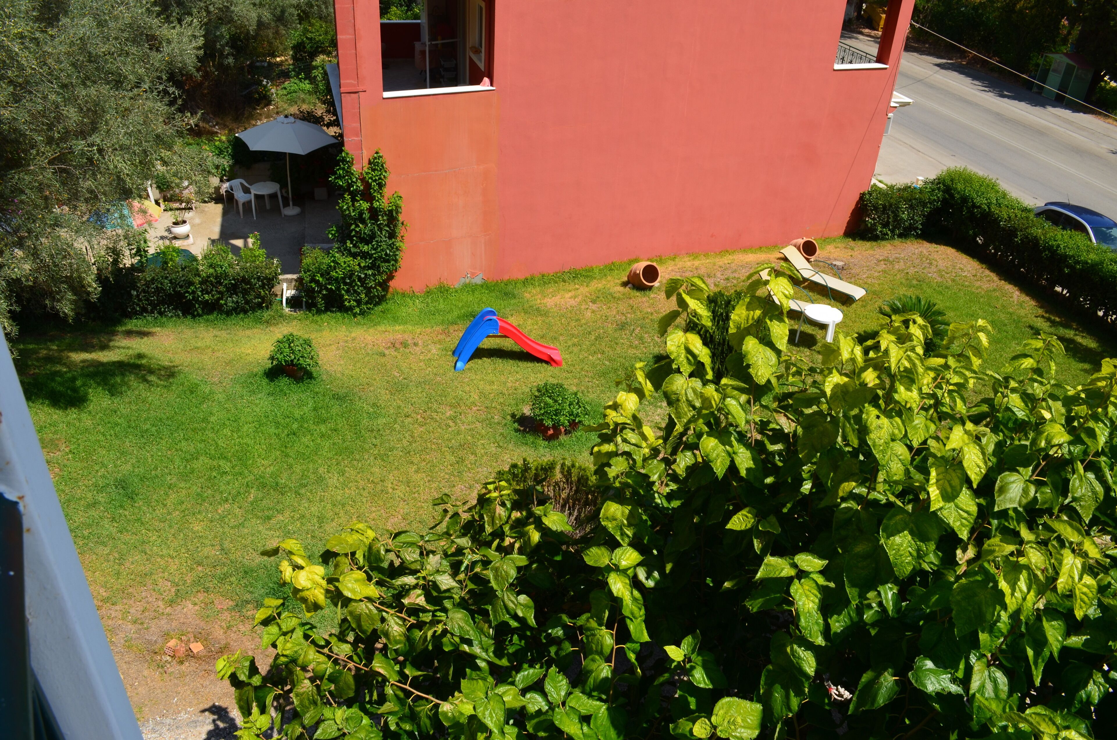 Edificio rojo con un pequeño jardín que incluye un tobogán y asientos.