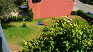 Edificio rojo con un pequeño jardín que incluye un tobogán y asientos.