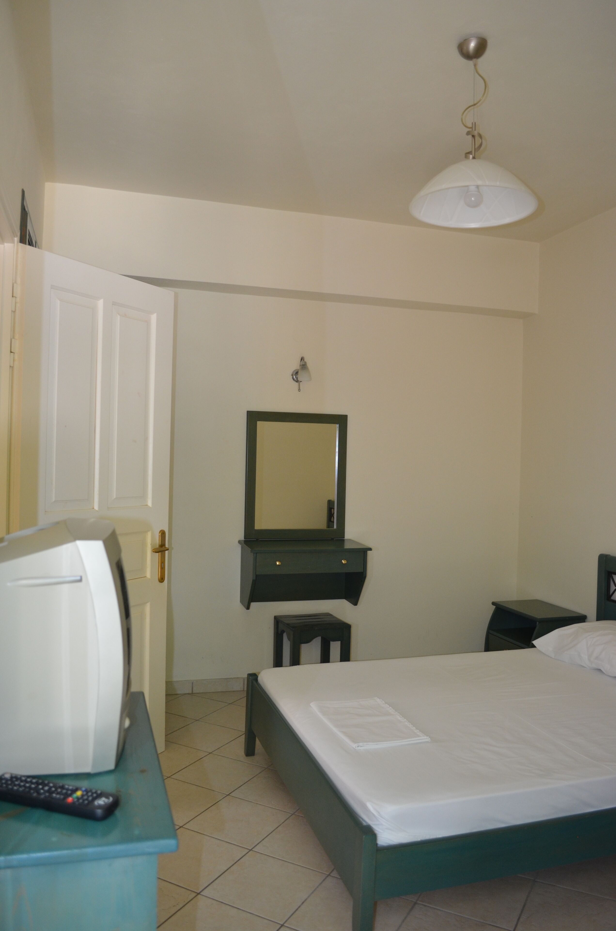 A bedroom with a bed, a dresser, a mirror, and a hanging light fixture.