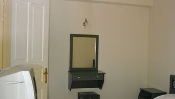 A bedroom with a bed, a dresser, a mirror, and a hanging light fixture.