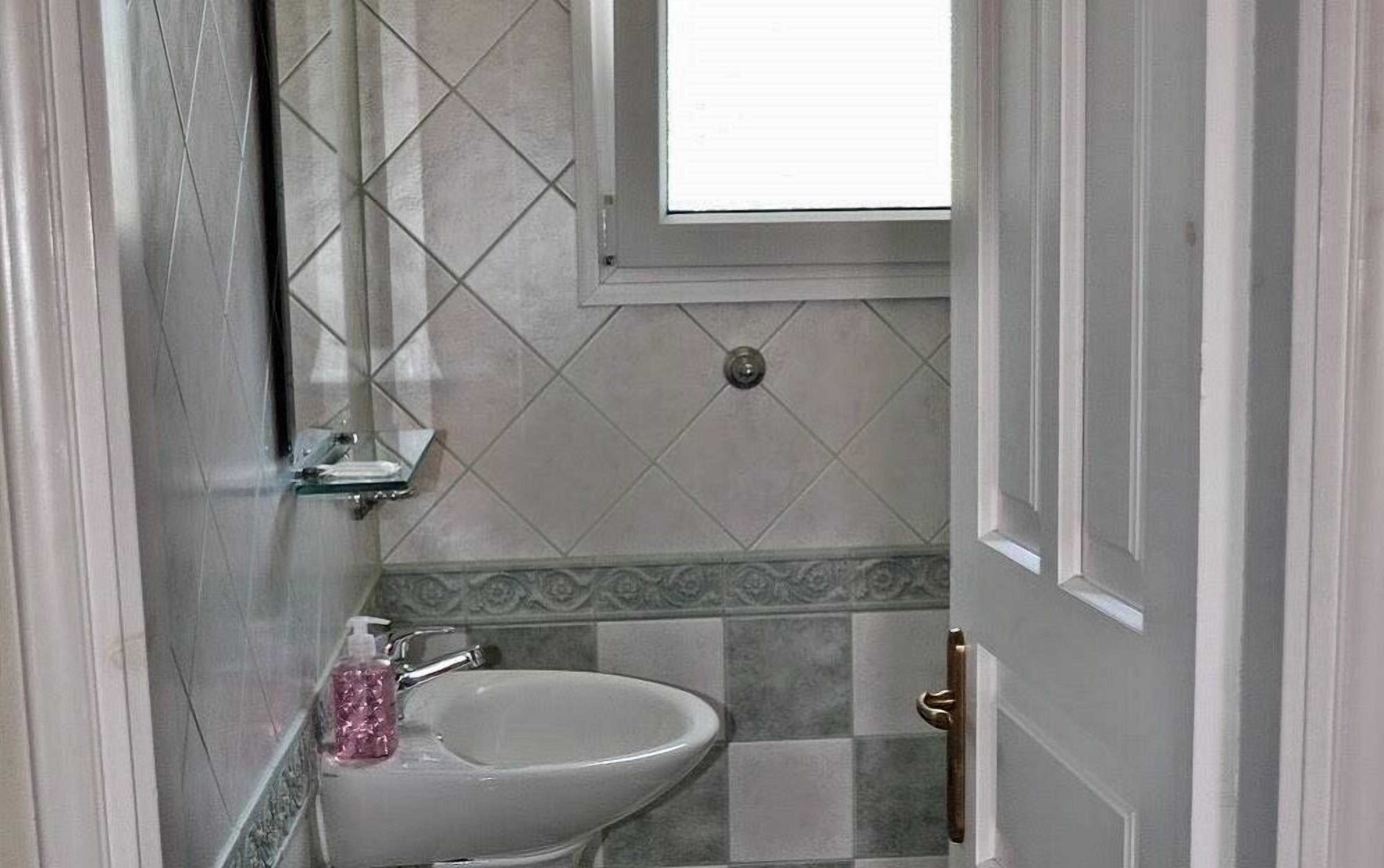 Une salle de bain avec un lavabo, une fenêtre et une porte.
