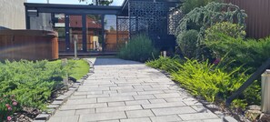 A paved pathway leading to a modern building with large windows and a decorative lattice structure. - Anita Apartments a Modern Riverside Boutique Hotel (XXI. kerület)