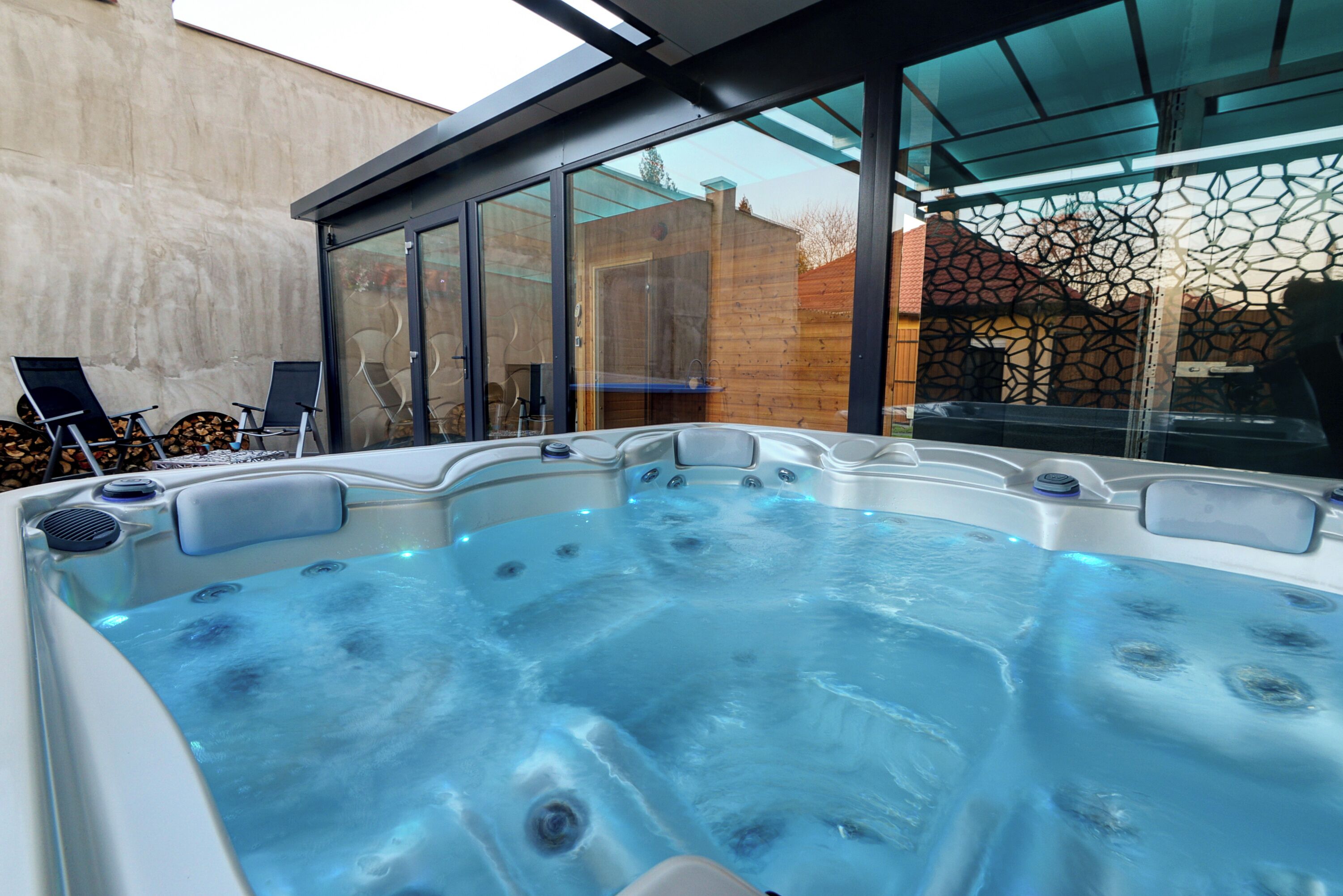 A hot tub with a glass enclosure, a wooden fence, and a clear sky.