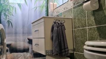 A bathroom with a toilet, a sink, a towel rack, and a shower curtain with a bamboo leaf design.