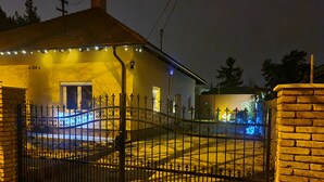 Uma casa com entrada protegida por portão, placa de identificação visível e fachada bem iluminada.