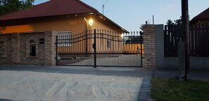 A gated property with a brick wall, a metal gate, and a red-tiled roof. - Anita Apartments a Modern Riverside Boutique Hotel (XXI. kerület)