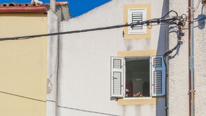 A building with two visible windows, one with shutters and one open. There is a staircase leading to an upper level. - Apartment Marija (Cres)