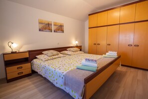 A bedroom with a bed, bedside tables, a wardrobe, and wall art. - Apartment Marija (Cres)