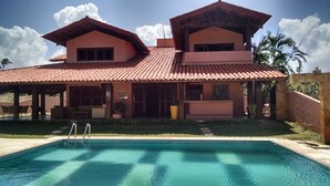 Una casa de dos pisos con una piscina al frente.