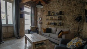 A rustic living room with stone walls, a wooden coffee table, a sofa, and a patterned throw pillow.
