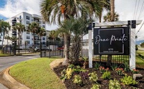 Welcome to Dune Pointe, a property with beautifully landscaped grounds and a multi-story building in the background.