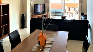 Een moderne woonkamer met een eethoek, een televisie en uitzicht op de omgeving.