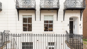 A white building with three balconies, a black wrought iron fence, and a door marked with the number 17. - L-spa Boutique Apartments No. 1A (Royal Leamington Spa)