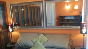 Een slaapkamer met een bed, kussens, een grote spiegel en twee bedlampjes.