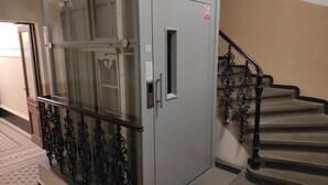 Een praktische ruimte met een metalen deur, een trap met gedetailleerd metalen spijlen en vloertegels met een patroon.