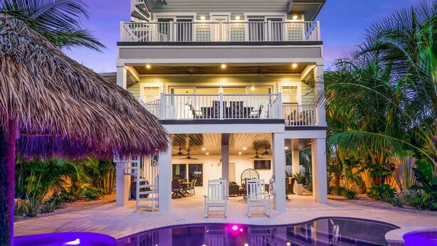 A two-story house with a balcony, a pool, and tropical landscaping. - Beach Views - Family-Friendly, Steps to Lido Beach! (Lido Key)