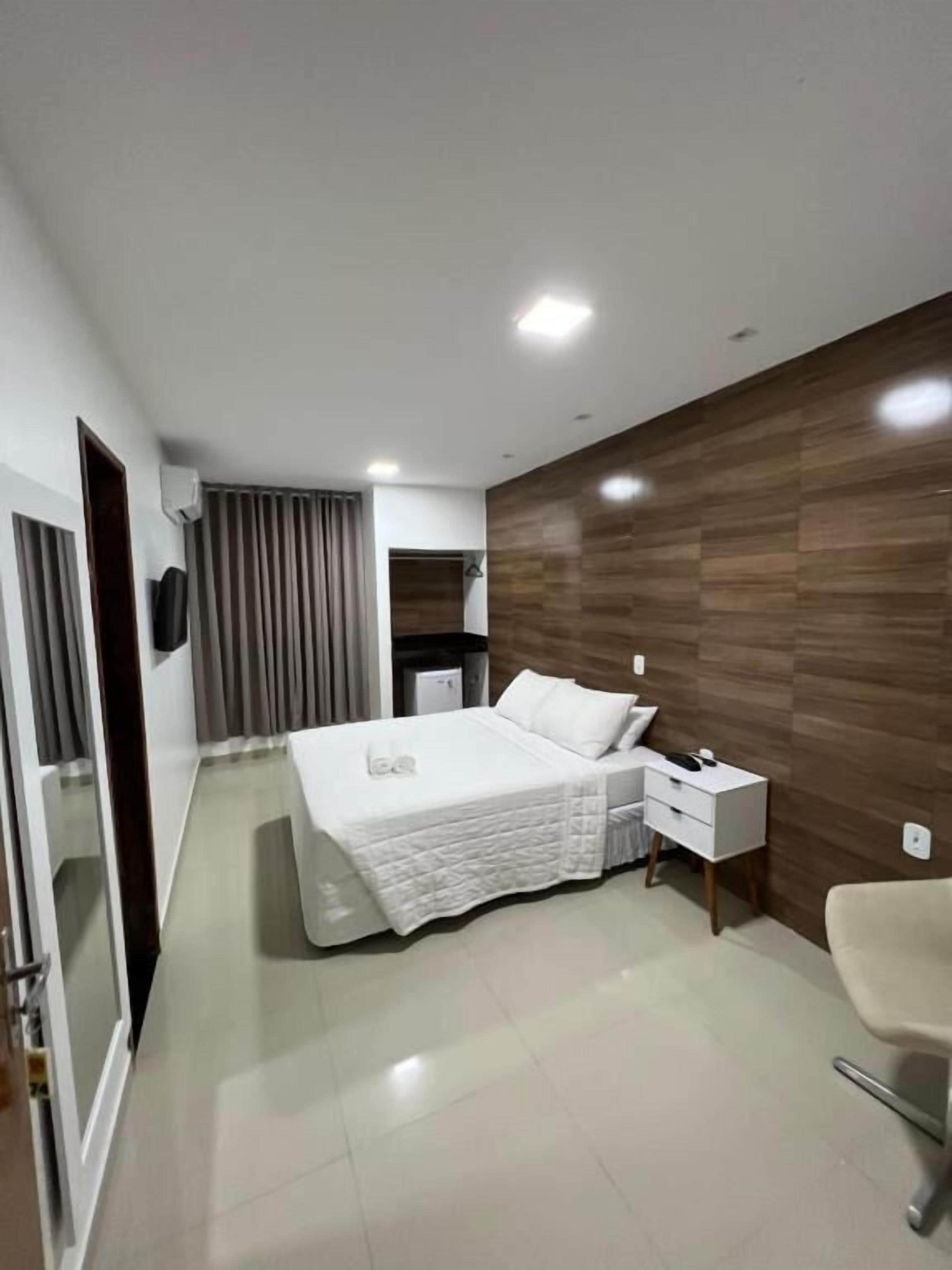 A modern hotel room with a bed, bedside table, and a chair.