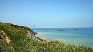 A coastal path leading to a beach with clear water and distant boats. - Studio proche de la Plage! (Auberville)