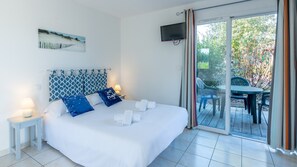 Ein Hotelzimmer mit Bett, Fernseher, Gemälde und Blick ins Freie.