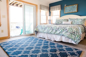 A bedroom with a bed, a blue patterned rug, a window with curtains, and a starfish decoration on the wall. - ☀️Steps to Beach, Private Pool & Hot Tub☀️ (Nags Head)