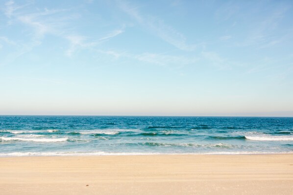 A beach with a clear sky and calm sea. - ☀️Steps to Beach, Private Pool & Hot Tub☀️ (Nags Head)
