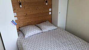 A single bed with patterned bedding, a wooden headboard, and two wall-mounted light fixtures. - Waterfront apartment with your feet in the water! (Langrune-sur-Mer)