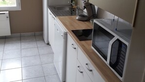 A modern kitchen with white cabinets, a wooden countertop, a built-in microwave, and a sink. - Waterfront apartment with your feet in the water! (Langrune-sur-Mer)