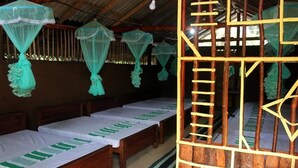 Una habitación con camas de madera, mosquiteras y una escalera de madera.