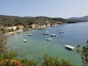 A coastal town with boats on the water, houses along the shore, and hills in the background. - Zmas Studios (South Pelion)