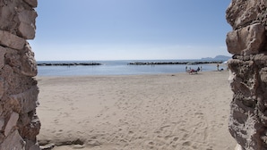 A beach with a clear sky, rocky cliffs, and a few people in the distance. - Formia Seaside Apartment With Beautiful Terrace (Formia)