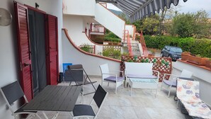 A terrace with a dining table and chairs, a staircase, and potted plants. - Formia Seaside Apartment With Beautiful Terrace (Formia)