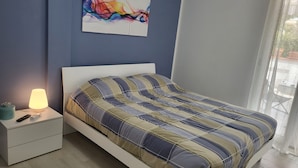 A bedroom with a bed, bedside table, lamp, and a colorful abstract painting on the wall. - Formia Seaside Apartment With Beautiful Terrace (Formia)
