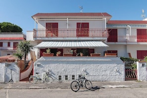 A two-story building with a balcony, potted plants, and a bicycle parked in front.