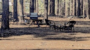 A campsite with a grill, tables, chairs, and a table with a tablecloth. - Grand Canyon Loft/Suite at Historic Wrigley Ranch-Horseback Ride-Target Shoot! (Parks)