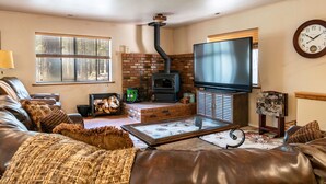 A living room with a fireplace, leather sofa, and a flat-screen TV. - Grand Canyon Loft/Suite at Historic Wrigley Ranch-Horseback Ride-Target Shoot! (Parks)